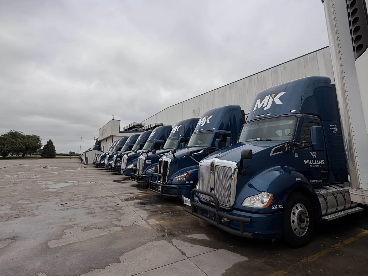 Row of MJ Kellner and Williams Dedicated semi trucks washed at the dock
